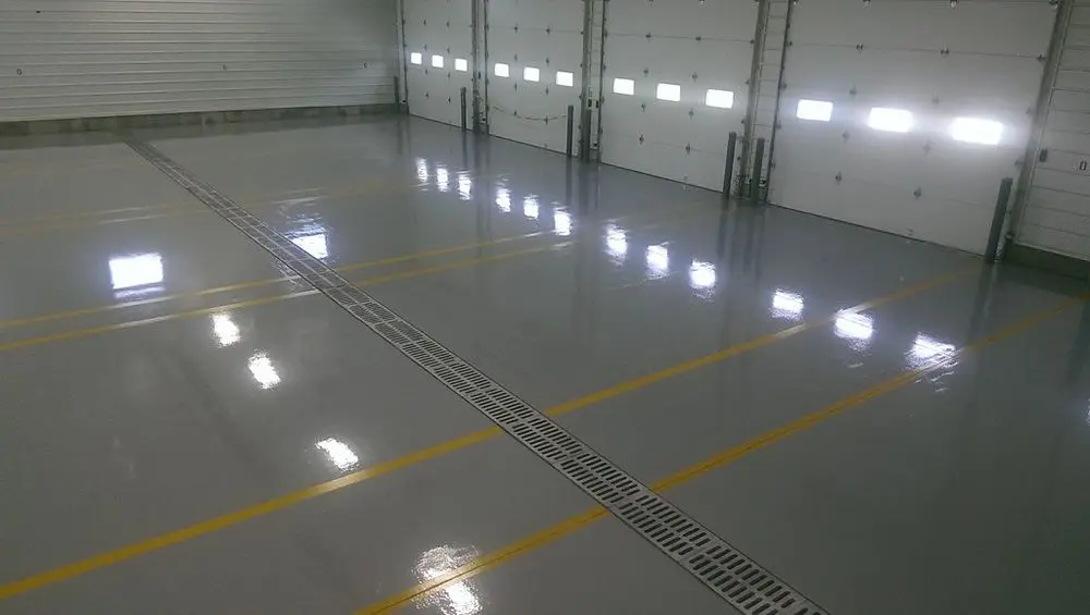 Glossy epoxy warehouse floor with yellow safety striping installed by Core Floorings Inc