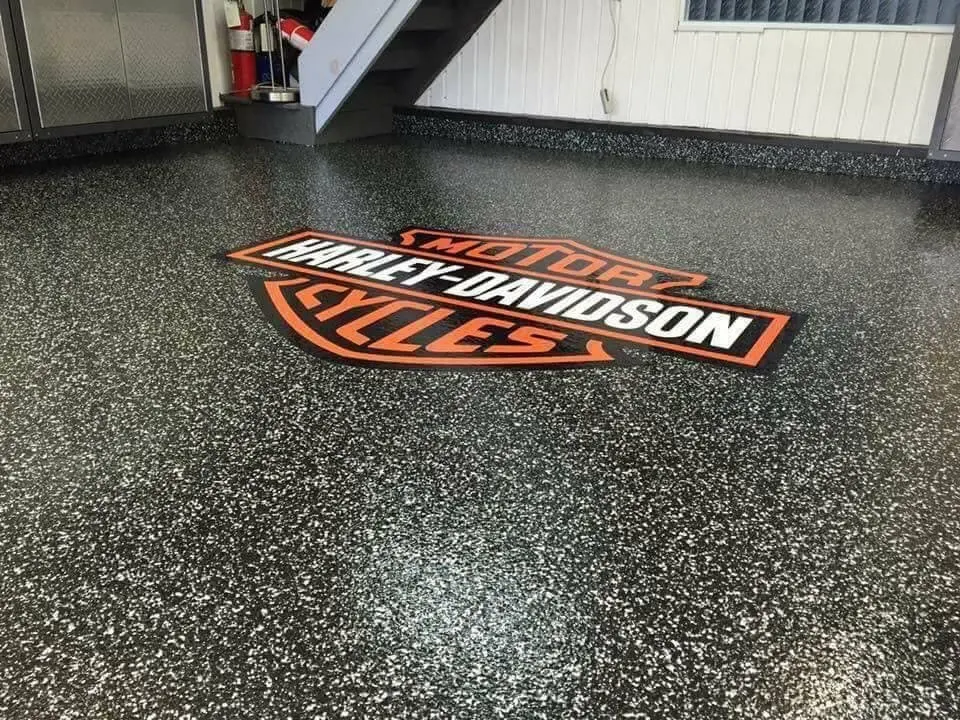 Black and white flake epoxy garage floor with a custom inlaid logo by Core Floorings Inc